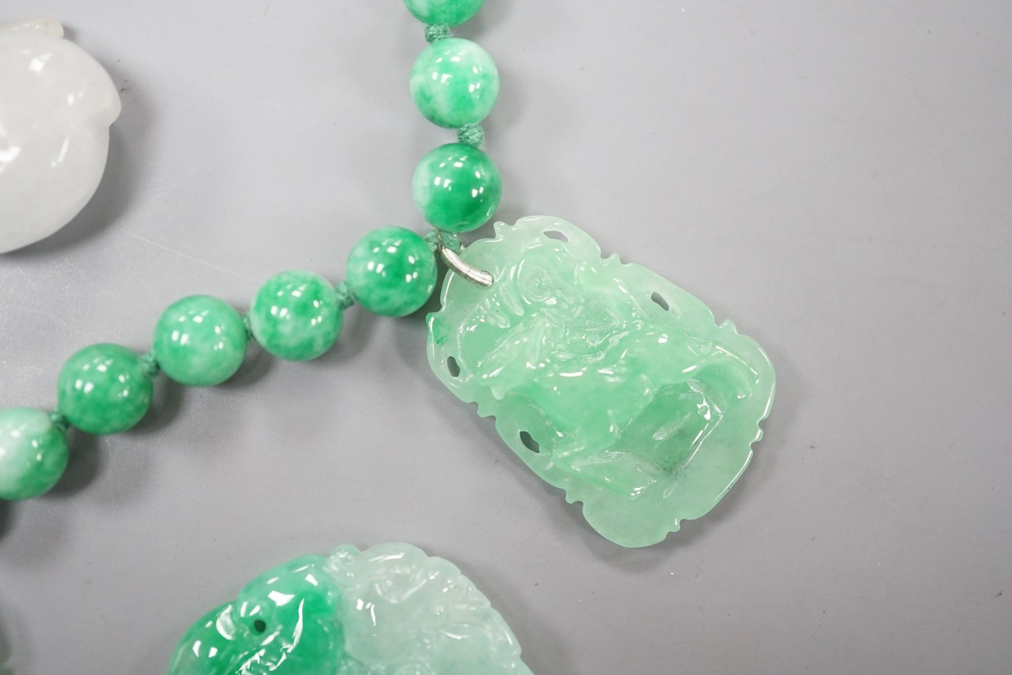 A jade bead necklace hung with three jade carvings, 49cm and three other jade carvings.